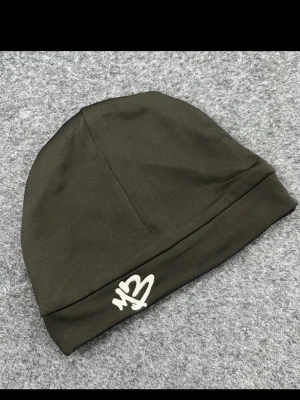 Svart mössa med broderad logga - Tillgänglig om några Dagar! Snygg svart mössa i mjukt tyg med vit broderad logga framtill. Enkel och stilren design som passar perfekt till streetwear eller casual outfits.