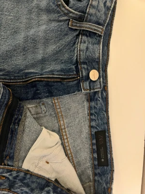 Blå raka jeans från ZARA - Säljer ett par klassiska blå jeans från ZARA med raka ben och hög midja. Jeansen har en snygg tvätt, gylf med dragkedja och knapp samt fem fickor. Perfekta till vardags och lätta att matcha med olika stilar.