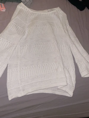 Vit stickad tröja från Micha - Säljer en vit stickad tröja från Micha i storlek S. Tröjan har ett luftigt hålmönster och långa ärmar, perfekt för lager-på-lager. Den har en rund halsringning och är mjuk och skön att bära. Passar dig som gillar enkel och stilren design.