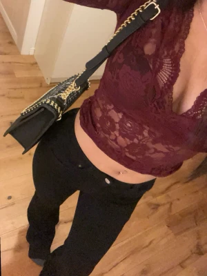 Vinröd spetsblus med v-ringning - Vinröd långärmad blus i spets med djup v-ringning och croppad passform. Blusen har blommigt spetsmönster och är transparent, perfekt för en trendig look. Snygg detalj med långa ärmar och figurnära modell.