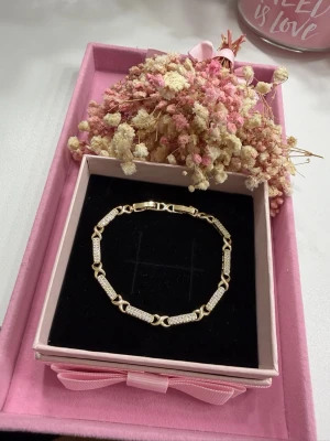 18k guldpläterat tennisarmband - Ett exklusivt och elegant tennisarmband tillverkat av rostfritt stål, pläterat med 18K guld för en lyxig och hållbar glans. Armbandet har ett dubbelt justerbart lås som ger perfekt passform, med en längd på 17 cm med ett lås och 19 cm med båda låsen. Dekorerat med gnistrande zirkonstenar som ger en feminin, sofistikerad och iögonfallande finish – perfekt för både vardag och fest.