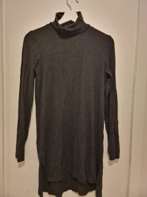 Mörkgrå långärmad polotröja  - En enkel och stilren mörkgrå polotröja med långa ärmar och rak passform. Perfekt att bära som lager under en jacka eller kavaj.