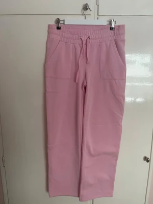 Mjukisbyxor - Säljer ett par ljusrosa mjukisbyxor med bred resår i midjan och snörning framtill. Byxorna har två stora fickor och raka ben för en chill och loose vibe. Perfekta för att mysa runt hemma eller hänga med vänner.