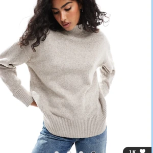 Beige stickad polotröja - Mysig beige stickad polotröja med ribbade muddar och hög krage. Tröjan har en loose fit och är perfekt för lager-på-lager under kyliga dagar. Enkel och stilren design som funkar till jeans eller kjol.