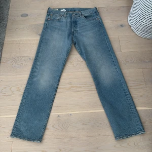 Levi's 501 ljusblå jeans W32 L32 - Klassiska Levi's 501 jeans i ljusblå tvätt med raka ben och femficksmodell. Jeansen har knappgylf och den ikoniska läderpatchen bak i midjan. Perfekta för dig som gillar en tidlös och avslappnad look.