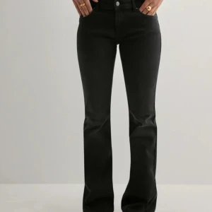 Svarta bootcut jeans med hög midja - Snygga svarta jeans med bootcut passform och låg midja. Jeansen har klassisk femficksdesign, bälteshällor och dragkedja med knapp. Materialet är stretchigt jeans för en bekväm känsla och tight passning upptill som släpper ut vid benslutet.