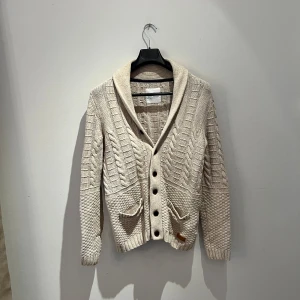 Beige stickad kofta från edc ESPRIT - Säljer en beige stickad kofta från edc ESPRIT i storlek medium. Koftan har snyggt kabelstickat mönster, bred krage, knappar framtill och två fickor. Perfekt för lager-på-lager och chill höst- eller vinterstil. Hör av er vid frågor 