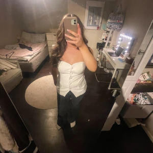 Vit korsett med knappar  - Säljer en vit korsett med stora dekorativa knappar framtill och en snygg spetsig nederkant. 