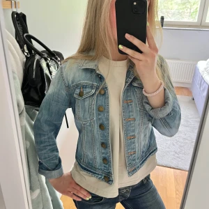 Ljusblå jeansjacka från MQ - Säljer en ljusblå jeansjacka från MQ med bronsfärgade knappar och två bröstfickor. Den är storlek S men är en kort modell.💕💕 inte mina bilder!! (Gammla ägarens)