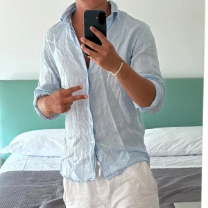 Ljusblå linneskjorta från Matinique - Fräsch helt ny ljusblå skjorta från Matinique i mjukt linne. Skjortan har klassisk krage, knappar framtill och lång ärm som enkelt kan rullas upp. Perfekt för sommarens chill dagar och har en loose passform som ger skön vibe. Nypris: 1699kr