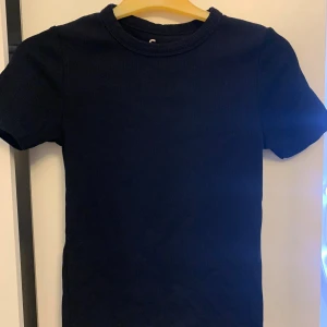 Svart t-shirt från FSBN Sister - En enkel och stilren svart t-shirt från FSBN Sister i storlek S. Modellen har rund hals och korta ärmar, tillverkad i mjuk bomull som känns skön mot huden. Perfekt för dig som gillar minimalistisk och clean stil.