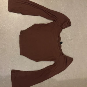 Brun ribbad långärmad topp - Säljer en brun långärmad topp med ribbad struktur och rund halsringning. Toppen har en slim passform och är perfekt att styla med jeans eller kjol för en trendig look.