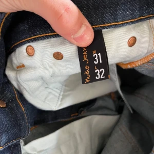 Nudie Jeans Thin Finn mörkblå jeans - Mörkblå Nudie Jeans Thin Finn, Jeansen har smal passform, klassiska bakfickor med Nudie-söm och orange kontrastsömmar. Materialet är 98% bomull och 2% elastan för lite stretch. Perfekta för dig som gillar en clean och stilren look.