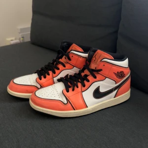 Nike Air Jordan 1 orange och vit storlek 44. Nypris( 1899kr) - Nike Air Jordan 1 sneakers i orange och vitt med svarta detaljer och snörning. Klassisk high-top siluett med svart Swoosh och Air Jordan-logga på sidan. Skorna har rund tå, platt sula och är tillverkade i skinn med perforering på tån för extra ventilation.