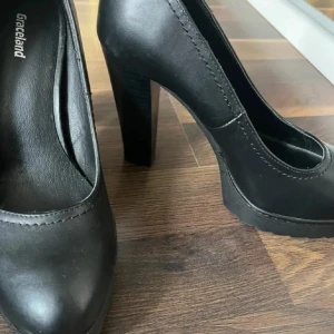 Svarta pumps från Graceland, storlek 38 - Klassiska svarta pumps från Graceland med rund tå och hög klack. Skorna är i syntetmaterial och har en stadig plattformssula som ger extra höjd och stabilitet. Perfekta för dig som vill ha en stilren och tidlös look.