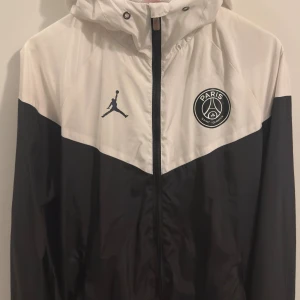 PSG träningsjacka - En riktig snygg träningsjacka/vindjacka av PSG. Perfekt för träning utomhus eller en helt vanlig promenad ute. Har använts max 2 gånger.  Har du några frågor eller vill ha fler bilder, tveka inte att fråga på!