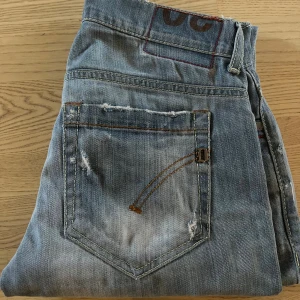 Blå slitna jeans från Dondup - Säljer ett par blå jeans från Dondup med slitningar i storlek 30. Är ganska små för sin storlek men annars fint skick och snygga till hösten