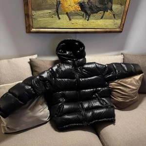 Svart pufferjacka från Zara  - Säljer en svart pufferjacka från Zara i storlek XL. Jackan har glansig finish, huva och dragkedja framtill. Perfekt för kalla dagar med sin oversized look och breda kanaler. Riktigt skön och trendig vinterjacka. Har en defekt i ena fickan, knapen har gått isönder och därefter blivit lagad inget som syns utan man måste väckla ut fickan för att se skadan.