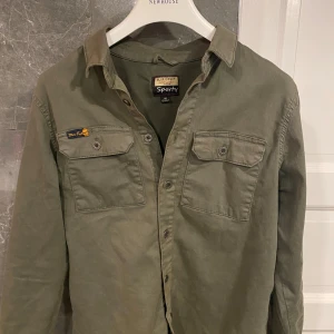 Olivgrön overshirt från Blue Effect - Olivgrön skjorta från Blue Effect med två bröstfickor med lock och knappar. Klassisk krage och knappstängning framtill. Skjortan är i bomull och har en avslappnad, lite loose passform. Perfekt för en cool och avslappnad stil.