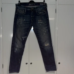 Replay Anbass W32/L30 - Säljer ett par eftertraktade Replay Anbass jeans i blå denim med slitna detaljer och snygg tvätt. Klassis slim  passform. Tydliga Replay-loggor och coola slitningar framtill och baktill. Perfekta för dig som gillar en avslappnad stil. Priset är absolut diskutabelt!
