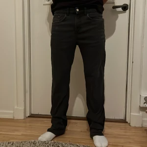 Svarta raka byxor från Lindex - Svarta byxor från Lindex med klassisk femficksdesign och raka ben. Byxorna har normal passform och är tillverkade i ett mjukt material som ger en snygg look. Perfekta för dig som gillar stilrena och enkla plagg.