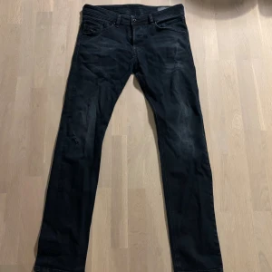 Svarta Diesel Belther jeans 32/34 - Svarta jeans från Diesel, modell Belther, med regular slim-tapered passform. Klassisk femficksdesign och diskreta slitningar. Jeansen är tillverkade i stretchigt denim för extra komfort och har en stilren look som funkar till det mesta.