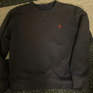 Mörkblå sweatshirt från Polo Ralph Lauren - Mårkblå sweatshirt från Polo Ralph Lauren med klassisk rund halsringning och röd broderad logga på bröstet. En stilren tröja som funkar till det mesta. Säljs för 500 kr, priset är ej hugget i sten och kan diskuteras vid en snabb affär!