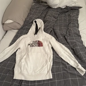 Vit hoodie från The North Face - Vit hoodie från the north face. Tröjan är i bra skick utifrån att den har klorin fläck på sig på märket och inuti luvan och en fläck på fickan på framtiden av hoodien, pris går att diskuteras