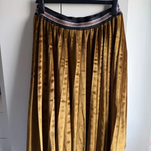 Ny Unmade Copenhagen brun kjol i sammet - ✨ Säljer en ny kjol i mjuk sammet från Unmade Copenhagen.  •L-XL. Utan storlekslapp •Kjolen har ett glittrigt elastiskt resårband i midjan. •Plisserad design som ger ett snyggt fall och extra volym.  •Perfekt för dig som gillar statement-plagg och lyxig känsla. •Kjolen är 71 cm lång och 37-38 cm bred i midjan. •Aldrig använd, endast tvättad.   🚭Djurfritt och rökfritt hem 💛 Se gärna mina andrs annonser samfrakt 