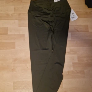 Mörkgröna leggings från SOC - Snygga mörkgröna leggings från SOC med hög midja och smal passform. Perfekta för träning eller chill, tillverkade i mjukt och stretchigt syntetmaterial som sitter skönt mot kroppen. Diskret design utan mönster och med taggar kvar.