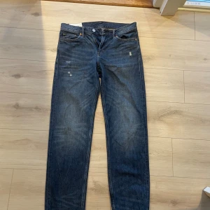 Blå relaxed fit jeans från H&M - Snygga blå jeans från H&M i relaxed fit med klassisk femficksdesign. Jeansen har en mörk tvätt med lätt slitna detaljer och raka ben. Perfekta för en chill och avslappnad stil. Tillverkade i bomull.
