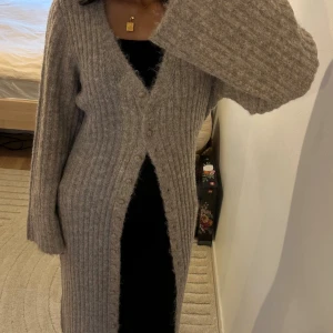 Beige ribbad lång stickad klänning - Säljer denna fina klänning/cardigan från NAKD, aldrig använd och prislappen är kvar.