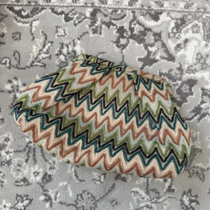 Mönstrad kuvertväska från Beck Söndergaard - Säljer en kuvertväska från Beck Söndergaard med zigzag-mönster i grönt, beige, brunt och svart. Väskan är tillverkad i bomull och har en dragkedja på insidan. Perfekt att ha med sig när du vill sticka ut lite extra.