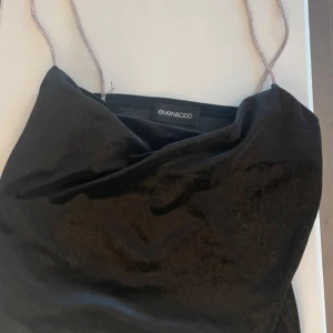 Svart sammetsklänning Even&Odd - Supersnygg svart sammetsklänning från Even&Odd med tunna glittriga axelband och draperad urringning. Perfekt för dig som vill ha en elegant och trendig look med lite extra glamour.