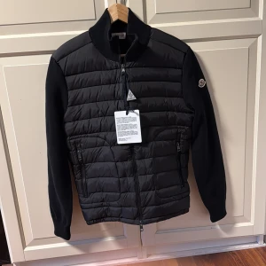 Moncler Cardigan - Tja! Säljer en sjukt snygg Moncler Cardigan i färgen svart. Sjukt snygg passar perfekt inför hösten nu och passar till både vardag och fest. NFC Scan finns!! Skick: 10/10 aldrig använd bara testad! Storlek: M men sitter som S passar mig som är 170cm och väger 55kg. Pris: 2200kr Pris kan diskuteras vid snabb affär💨Kom DM vid fler bilder eller funderingar🥰