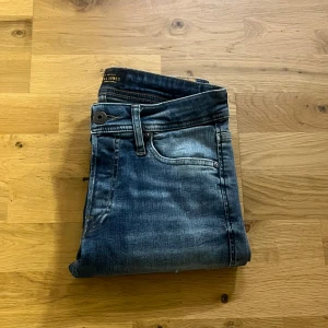 Slim fit jeans från Jack & Jones - Snygga blå slim fit jeans från Jack & Jones med slitna detaljer och klassisk femficksdesign. Jeansen har en något ljusare tvätt framtill och är tillverkade i ett mjukt bomullsmaterial med lite stretch för extra komfort. Går la självklart att pruta 