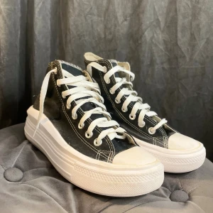Converse All Star svart platform - Svarta Converse All Star sneakers med vit plattformssula och klassisk rund tå. Skorna har vita snören, kontrasterande vita sömmar och logotyp på sidan. Perfekt för dig som vill ha lite extra höjd och cool stil.