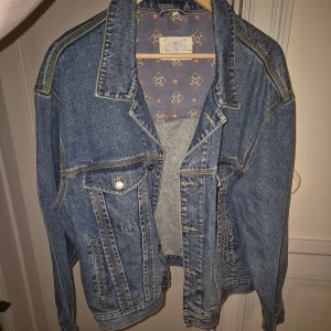 Oversized jeansjacka med mönstrat foder - Snygg oversized jeansjacka i klassisk blå denim med coola kontrastsömmar och mönstrat foder. Jackan har stora fickor med knappar och bred krage. Perfekt för dig som gillar retrovibe och vill ha en chill look.