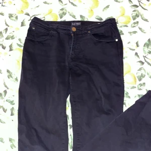 Svarta jeans från Armani Jeans - Svarta jeans från Armani Jeans med klassisk femficksdesign och snygg logga på bakfickan. Byxorna är tillverkade i bomull med lite stretch för skön passform. Perfekta för dig som gillar stilrena och tidlösa jeans.