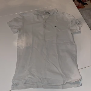 J.Lindeberg piké - Vit pikétröja från J.Lindeberg i slim fit-modell. Klassisk krage, korta ärmar och två knappar framtill. Liten svart broderad logga på bröstet. Tillverkad i bomull för en skön känsla och stilren look. 