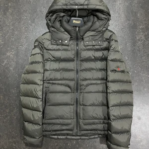 Mörkgrön pufferjacka från 49winters - Mörkgrön pufferjacka från 49winters med huva och två dragkedjeförsedda fickor framtill och inuti . Använd men fortfarande väldigt fräsh Perfekt för dig som gillar streetstyle och vill hålla dig varm.