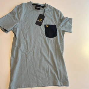 Lyle and scott t-shirt - En helt oanvänd ljusblå lyle and scott T-shirt med en broderad ficka på bröstet. Passar perfekt för dig som vill ha en stilren och modern outfit! Pris går såklart att diskuteras 👍 