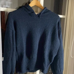 Mörkblå stickad hoodie Gina Tricot - Mysig mörkblå stickad hoodie från Gina Tricot i storlek 158/164. Tröjan har huva, långa ärmar och ribbade muddar vid ärmslut och nederkant🩷
