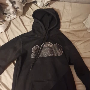 Svart Trapstar hoodie - Svart hoodie från Trapstar med stort silvrigt tryck på bröstet där det står 'Trapstar London Shooters'