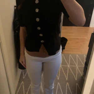 Elegant svart tröja med skinande knappar. - Det är en svart tröja som har knappar som formar sig som blommor, den sitter lagom tajt och lagom löst och är inte obekväm. Tröjan har ett mjukt material.💕