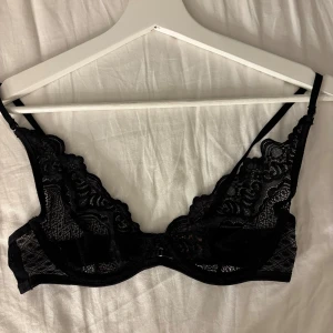 Svart spets bh från Hunkemöller - Säljer en svart spetsbh från Hunkemöller i storlek 70C. Den har tunna axelband, vacker spets med blommigt mönster och en klassisk hakknäppning bak. Perfekt för dig som gillar detaljer och vill ha något extra snyggt under kläderna.