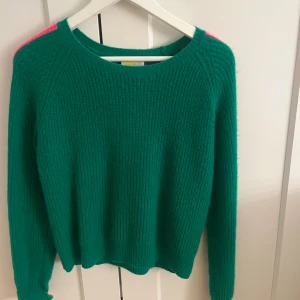 Grön stickad tröja From Future XS - Säljer en grön stickad tröja från From Future i storlek XS. Tröjan har långa ärmar med coola rosa detaljer längs axlar och ärmar. Mjuk och skön med rund halsringning, perfekt för dig som gillar färg och vill sticka ut.