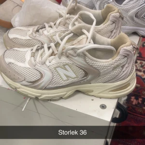 Beige New Balance sneakers strl 36 - Säljer ett par snygga New Balance sneakers i beige och vitt med mesh och syntetdetaljer. Skorna har rund tå, snörning och en chunky platt sula. Perfekta för dig som gillar sportig och trendig stil.