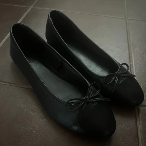 Svarta ballerina­skor från H&M - Snygga och klassiska ballerina i svart med söt rosett­detalj framtill. Endast testade en gång men tyvärr fel storlek! Perfekta både till vardags och fest. Storlek 37💓💓