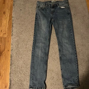 Blå jeans från 157, straight fit - STORLEK 160 CM.Ett par klassiska blå jeans från 157 med raka ben och normal passform. Jeansen har fem fickor, dragkedja och knapp framtill samt snygga slitningar för en avslappnad look. Perfekta till sneakers eller boots och funkar året runt.
